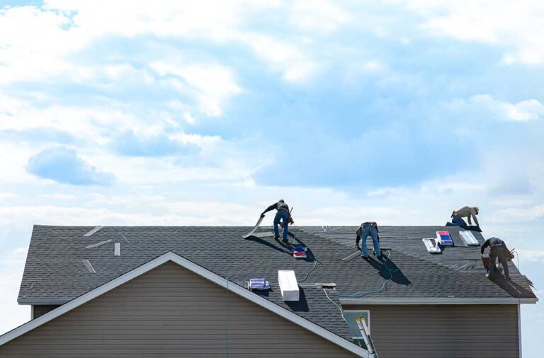 A close-up of a roof showing curled and cracked asphalt shingles under daylight.