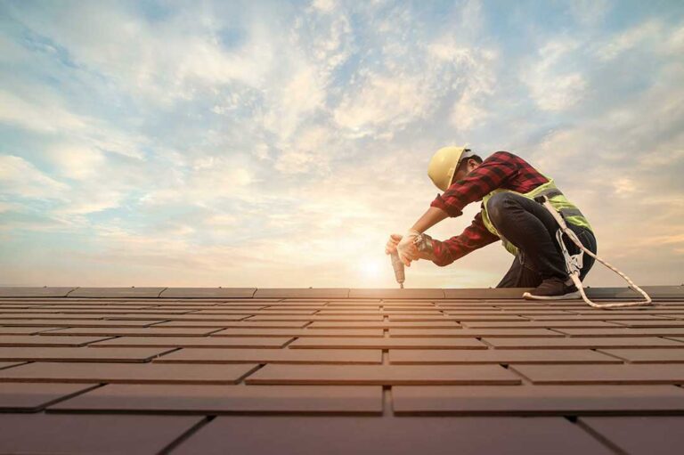 A homeowner examines a damp attic ceiling beneath stained roof insulation after a leak.