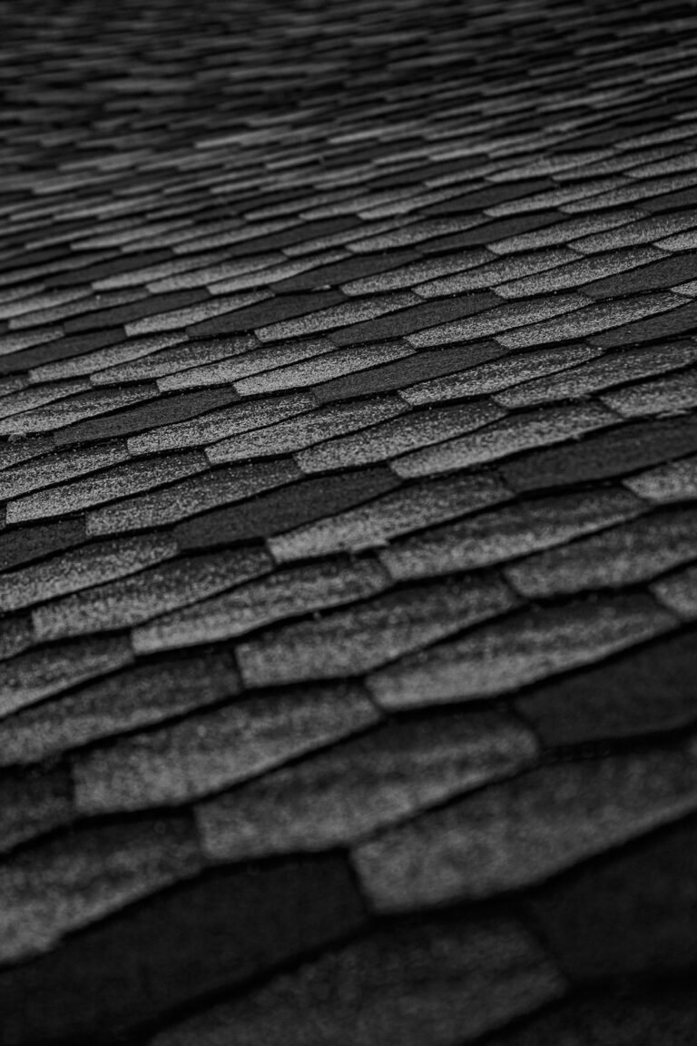 Installer unrolls protective underlayment across a clean roof deck before shingles are installed.