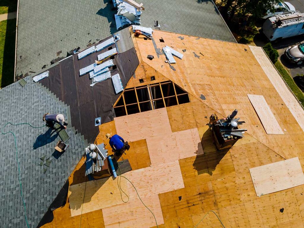 A residential roof with a skylight, layered flashing, and light snow surrounding the frame.